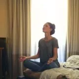 Femeie care practică relaxarea, așezată pe pat