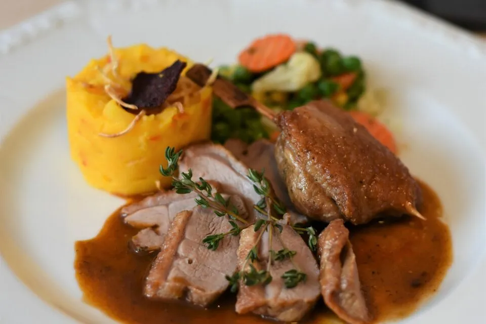 Felii de dovleac coapte pe o tavă, lângă un cuțit și ierburi aromatice
